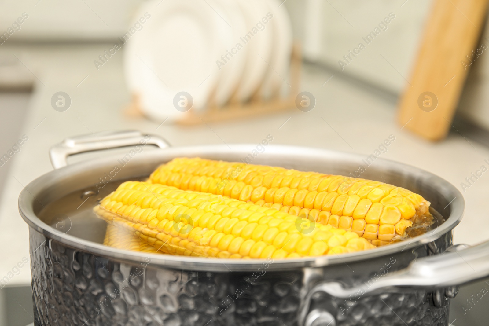 Photo of Pot with boiling fresh corn in kitchen, closeup