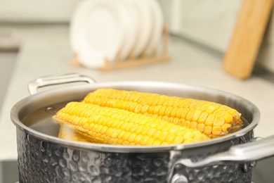 Pot with boiling fresh corn in kitchen, closeup