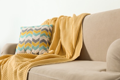 Photo of Cozy sofa with pillow and plaid near light wall. Idea for living room interior design