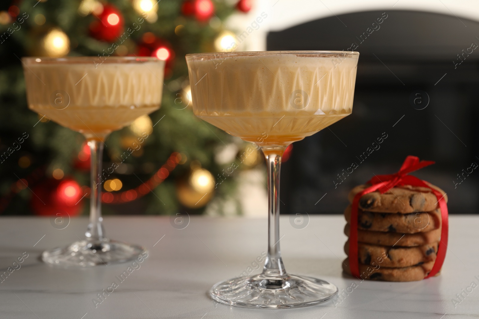 Photo of Tasty eggnog and cookies on white marble table indoors