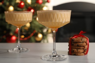 Photo of Tasty eggnog and cookies on white marble table indoors
