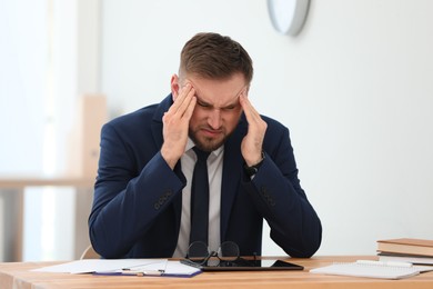 Photo of Man suffering from migraine at workplace in office