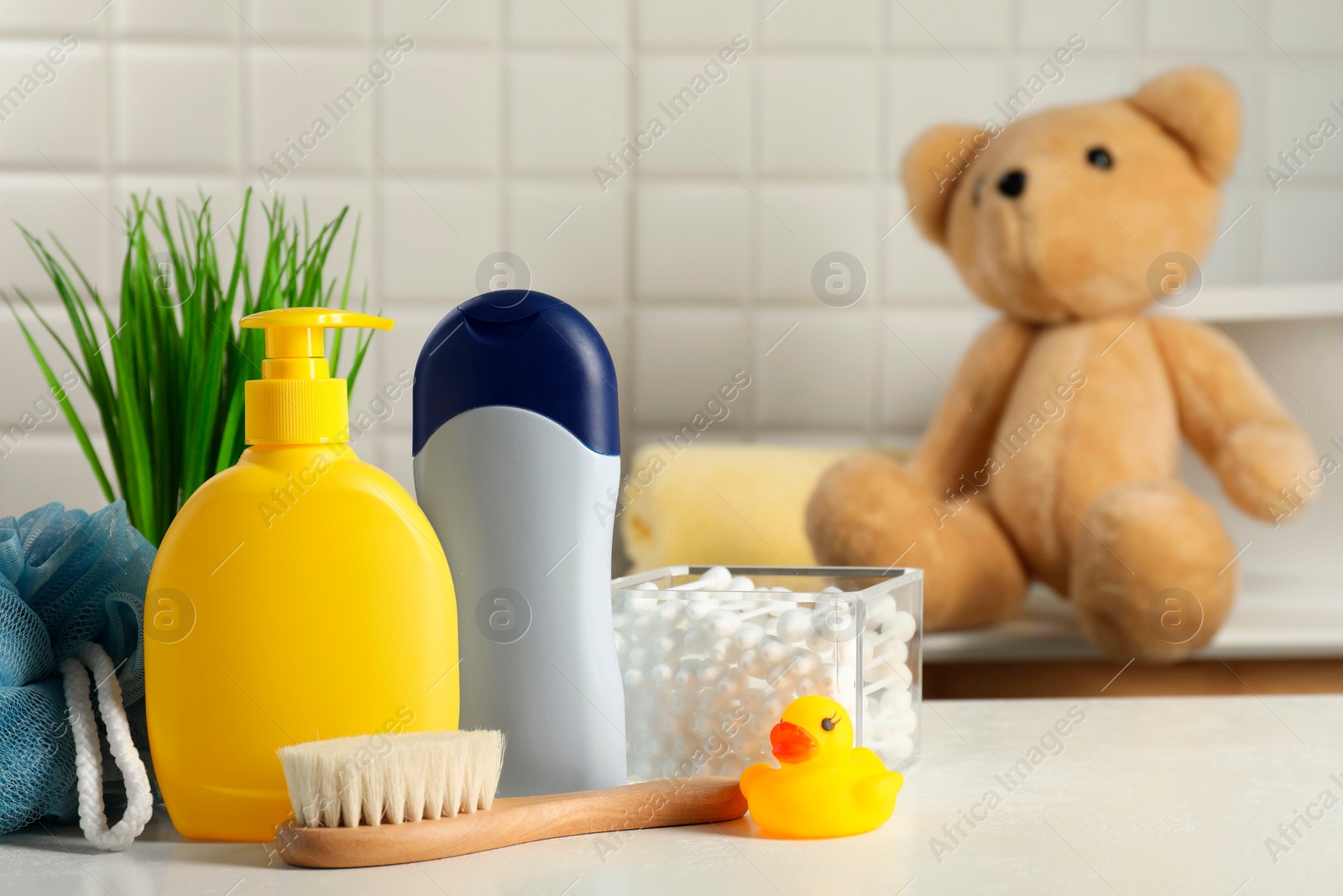 Photo of Baby cosmetic products, bath duck, brush and cotton swabs on white table. Space for text