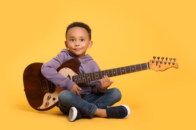 Photo of African-American boy with electric guitar on yellow background
