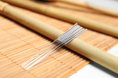 Photo of Many acupuncture needles on bamboo mat, closeup