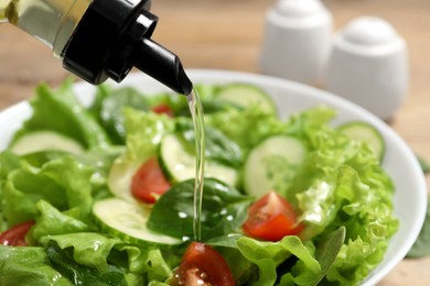 Photo of Pouring oil into tasty salad on table, closeup