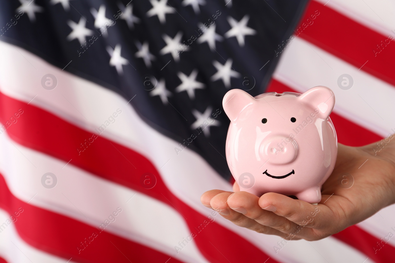 Photo of Woman holding piggy bank against American flag, closeup. Space for text