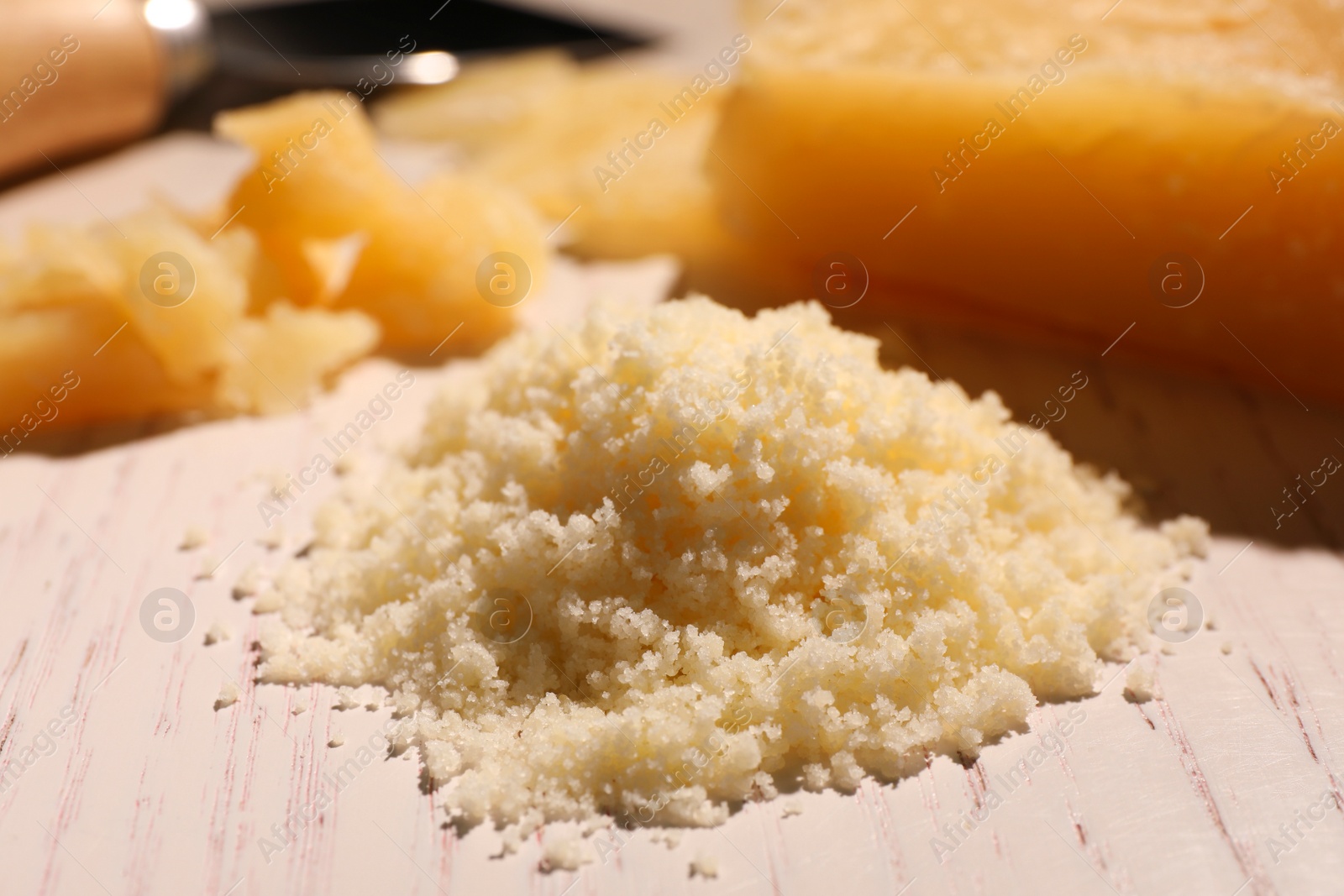 Photo of Delicious grated parmesan cheese on white wooden table, closeup