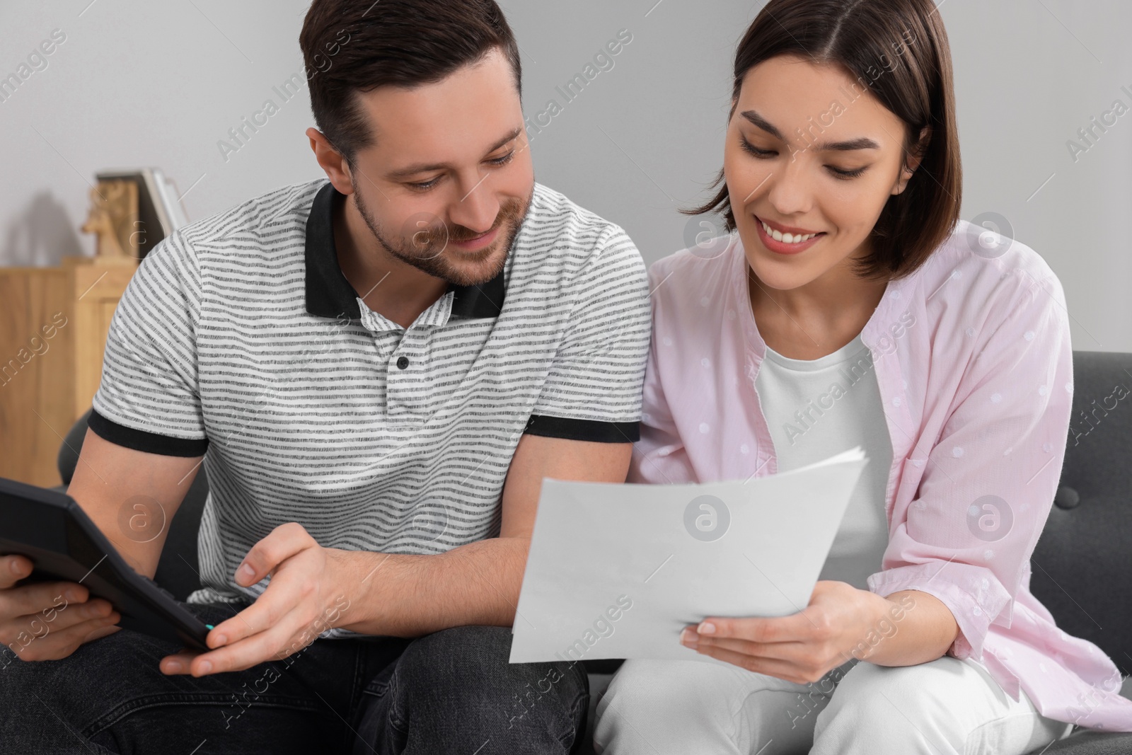 Photo of Young couple with papers discussing pension plan indoors