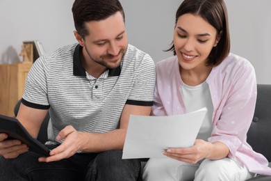 Photo of Young couple with papers discussing pension plan indoors