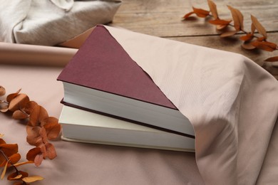 Photo of Furoshiki technique. Books, dry branches and beige fabric on table