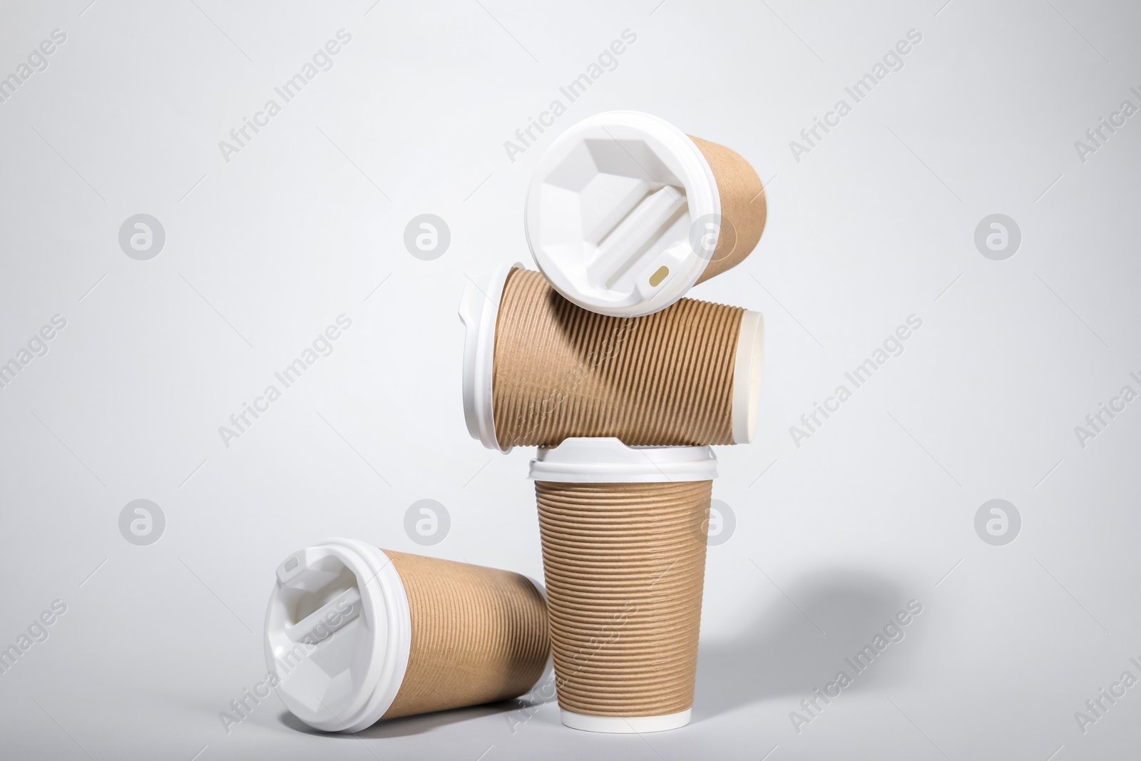 Photo of Paper cups with white lids on light gray background. Coffee to go