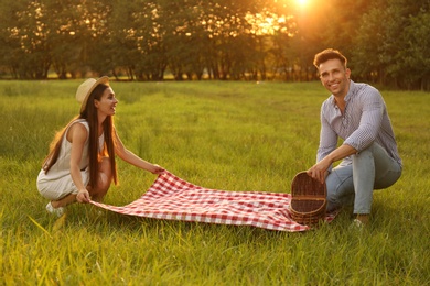 Young couple with picnic blanket and basket in park