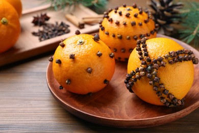 Photo of Pomander balls made of tangerines with cloves on wooden table