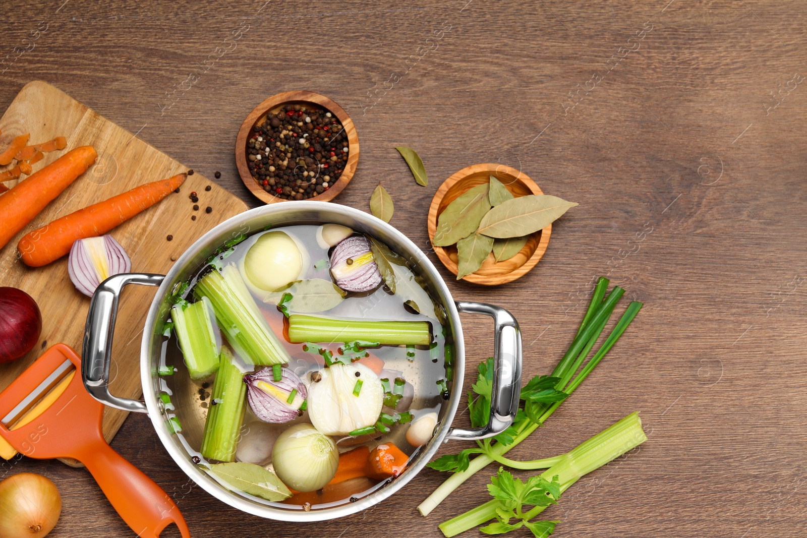 Photo of Pot and different ingredients for cooking tasty bouillon on wooden table, flat lay. Space for text