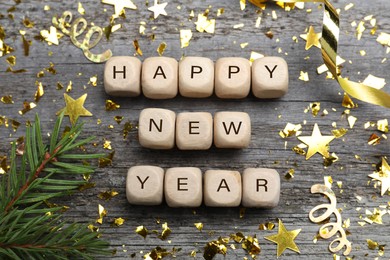 Phrase Happy New Year 2022 made of cubes and festive decor on grey wooden background, flat lay