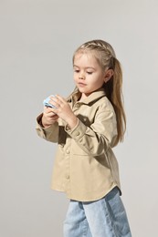 Fashion concept. Stylish girl with toy camera on light grey background