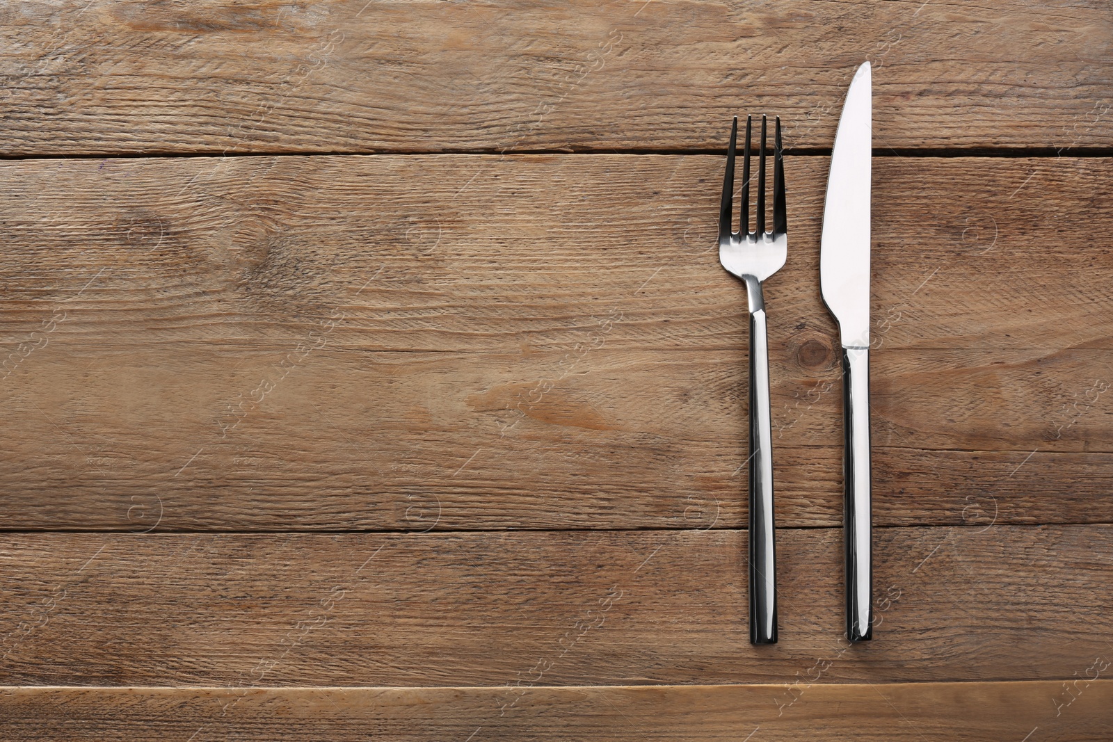 Photo of Fork and knife on wooden table, flat lay with space for text. Stylish shiny cutlery set