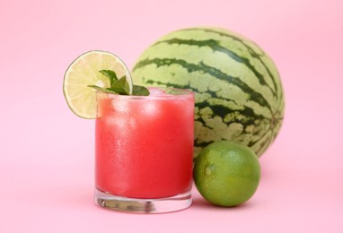 Photo of Glass of delicious watermelon drink with mint, lime and fresh fruits on pink background