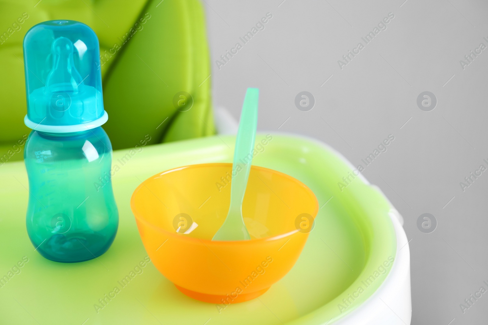 Photo of Set of plastic dishware on white feeding table. Serving baby food