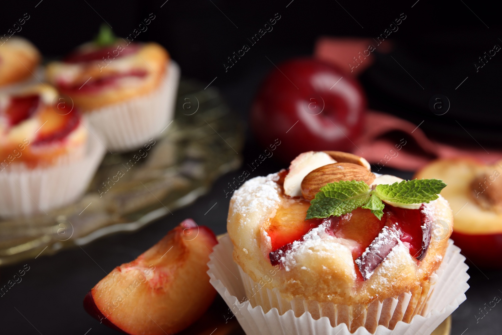 Photo of Delicious cupcakes with plums on black background, closeup