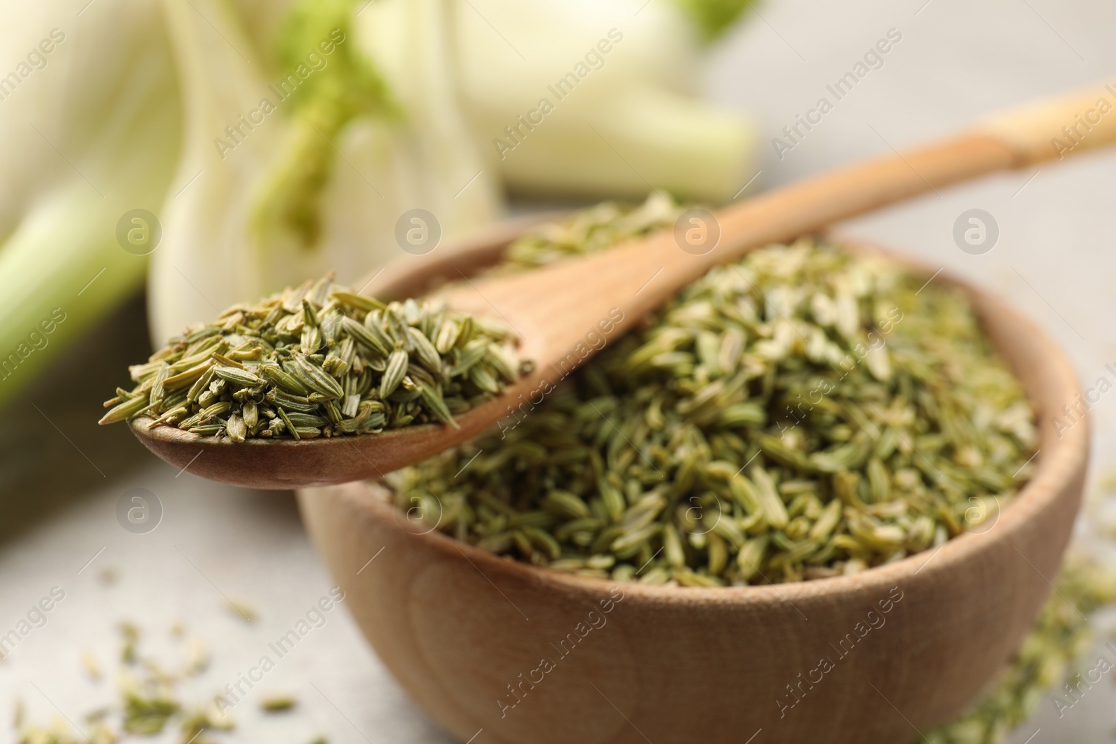 Photo of Bowl and spoon with fennel seeds on table, closeup