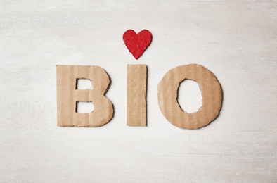 Photo of Word "Bio" made of cardboard letters and heart on light background, top view