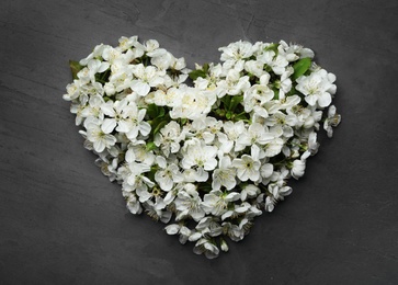 Heart made of beautiful fresh spring flowers on color background, top view