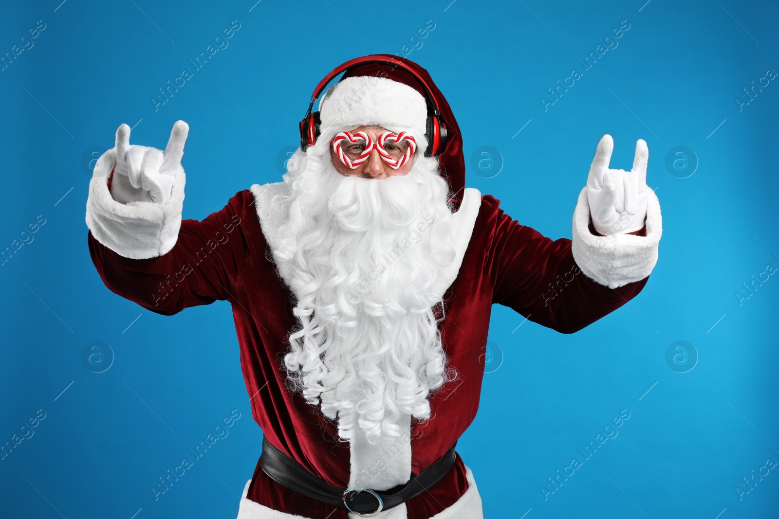 Photo of Santa Claus with headphones listening to Christmas music on blue background