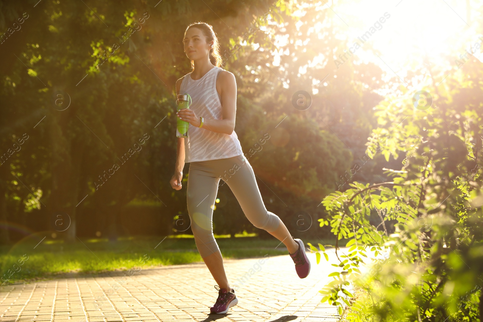 Photo of Young woman running in park on sunny day