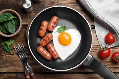 Photo of Romantic breakfast with fried sausages and heart shaped egg on wooden table, flat lay. Valentine's day celebration