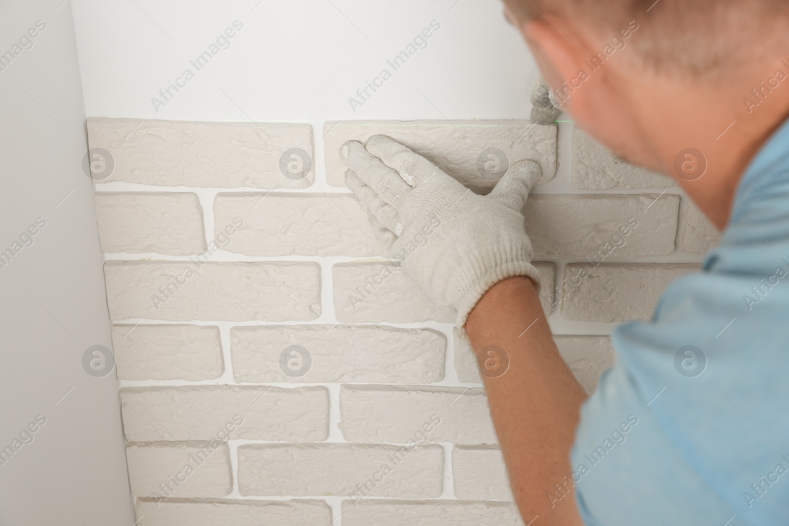 Photo of Worker installing decorative wall tiles in room, closeup