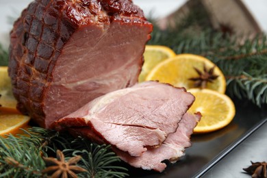 Photo of Delicious ham served with orange and fir branches on plate, closeup. Christmas dinner