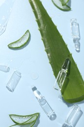 Photo of Flat lay composition with skincare ampoules and aloe leaves on light blue background