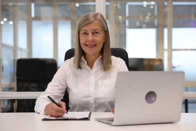 Photo of Smiling woman with clipboard and laptop working in office. Lawyer, businesswoman, accountant or manager