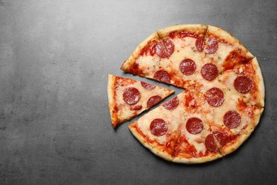 Photo of Hot delicious pepperoni pizza on grey table, top view. Space for text