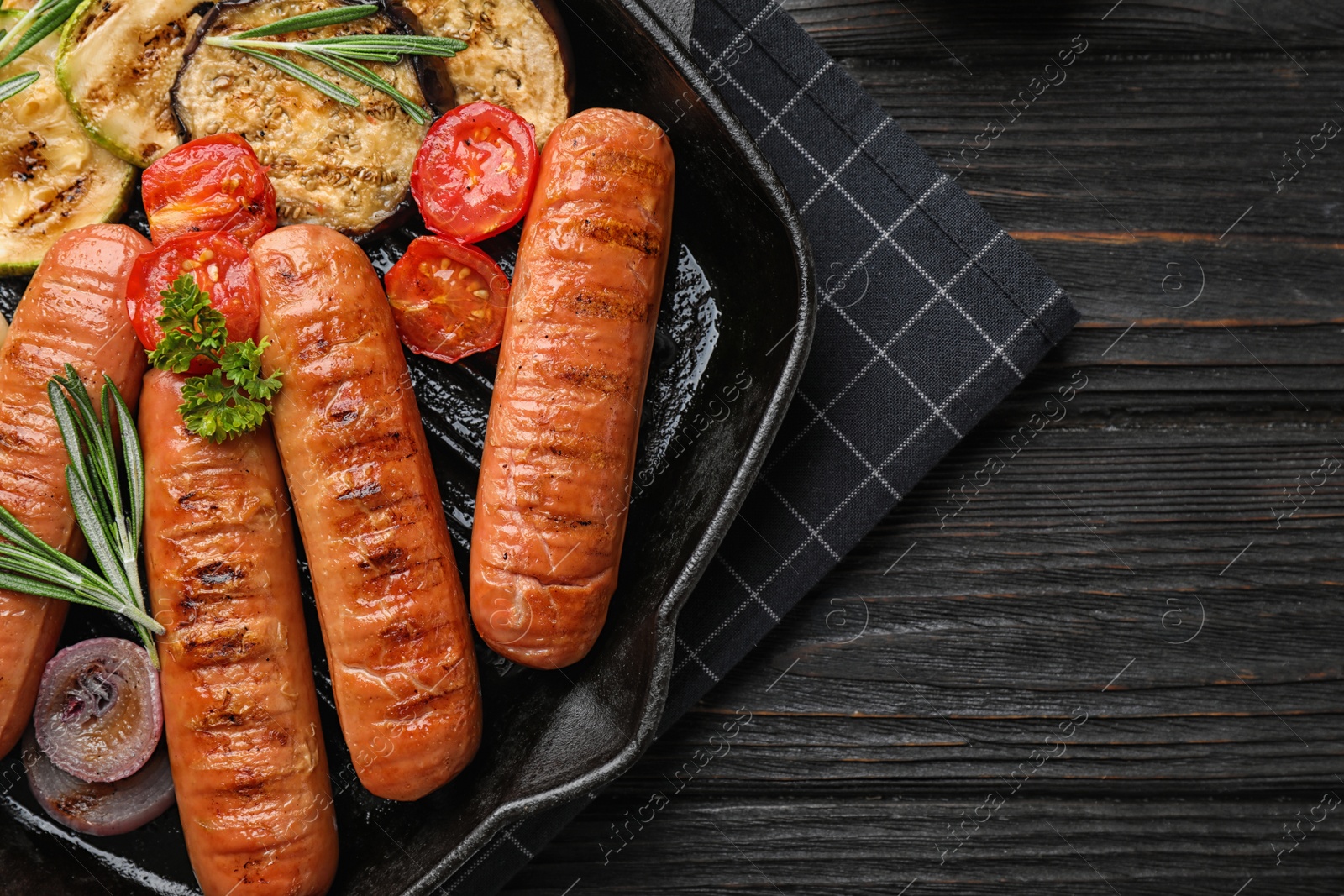 Photo of Delicious grilled sausages with vegetables on dark wooden table, top view. Barbecue food