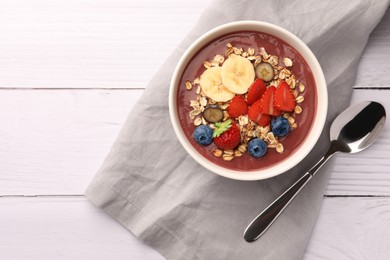 Delicious smoothie bowl with fresh berries, banana and granola on white wooden table, flat lay. Space for text