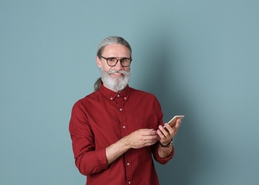 Photo of Handsome mature man with mobile phone on color background