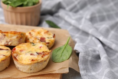 Delicious egg muffins with cheese and bacon on grey table, closeup. Space for text