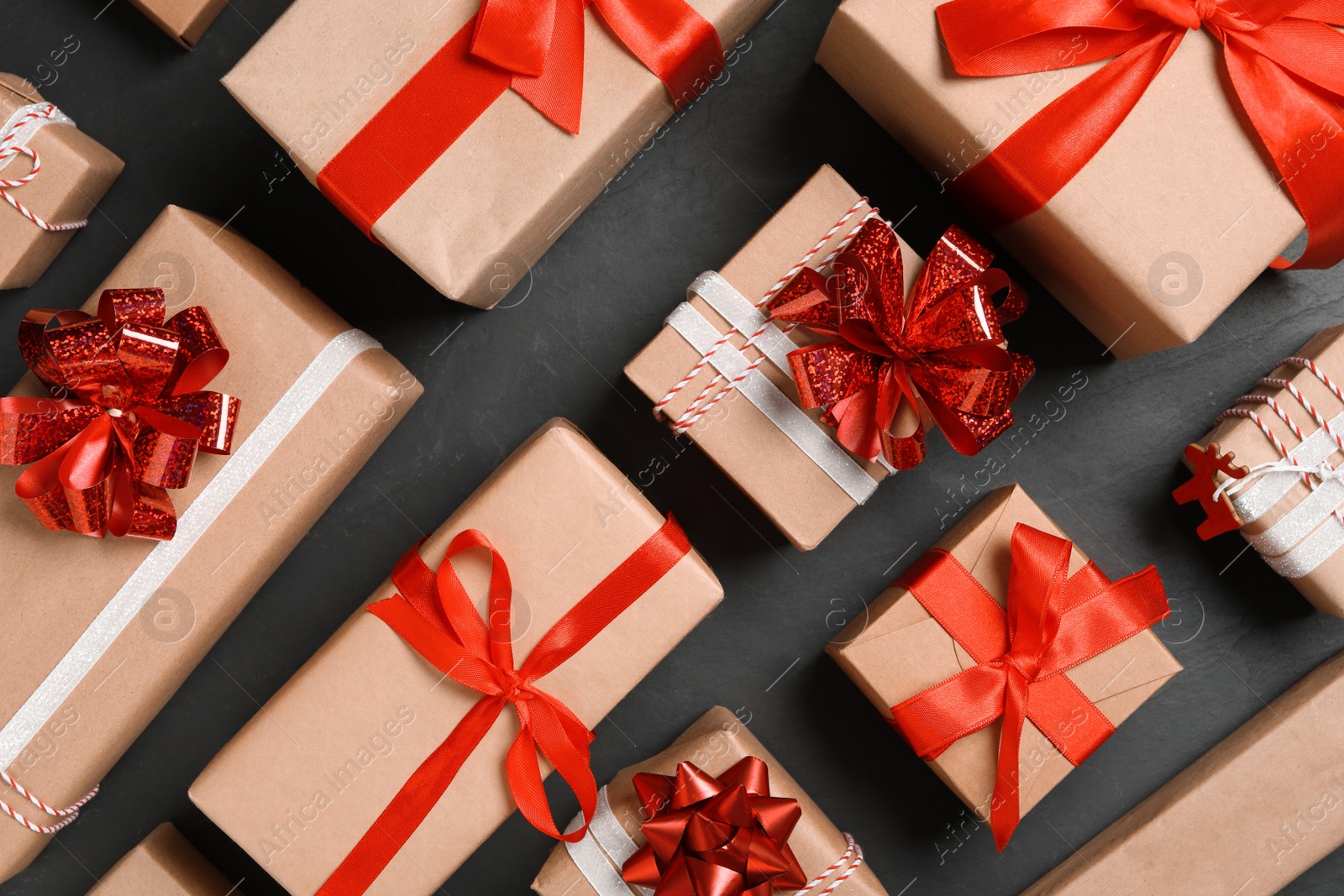 Photo of Christmas gift boxes with red bows on dark grey background, flat lay