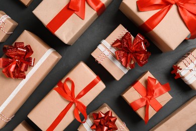 Photo of Christmas gift boxes with red bows on dark grey background, flat lay