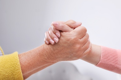 Photo of People holding hands together indoors. Help and elderly care service