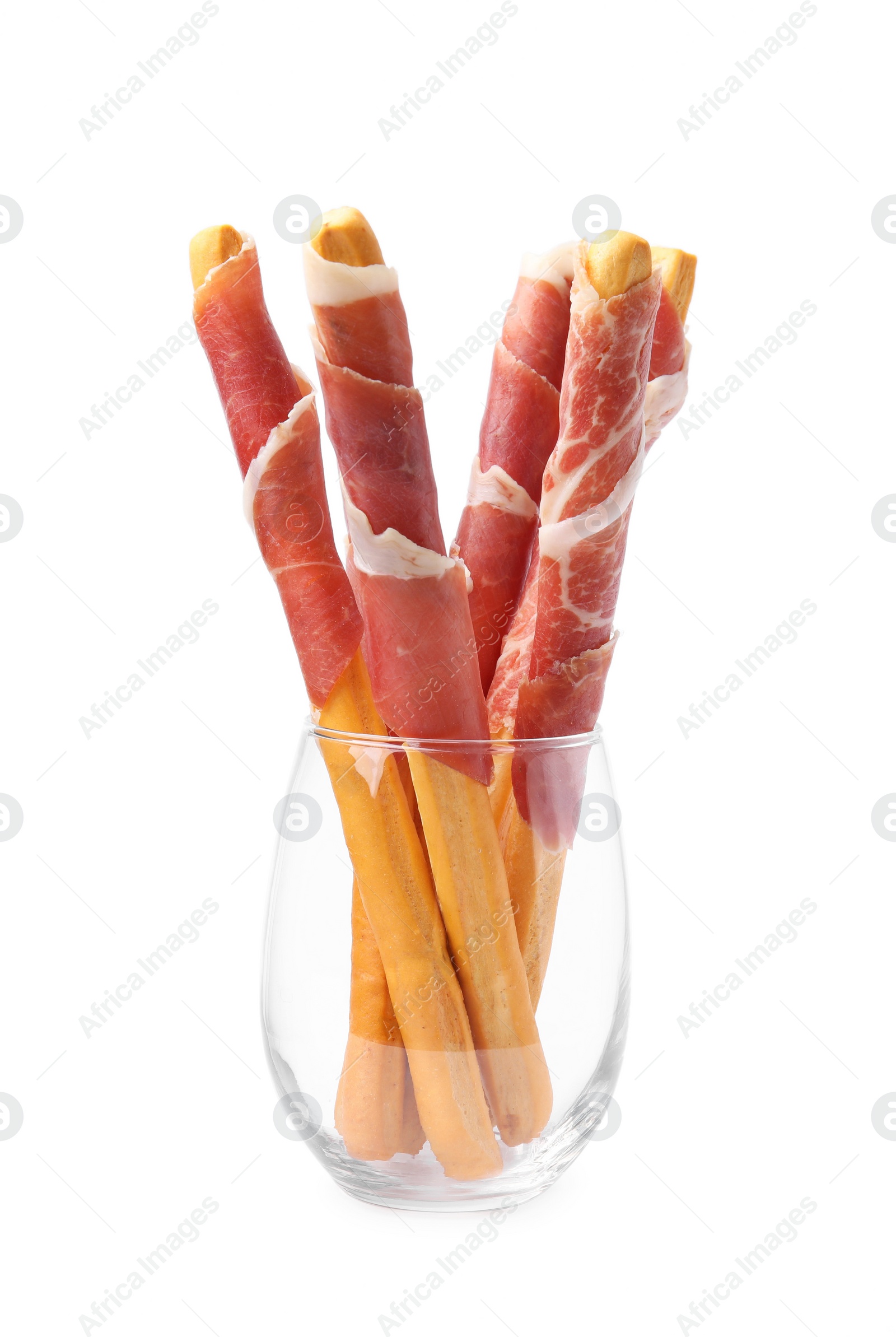 Photo of Tasty grissini sticks with prosciutto in glass isolated on white