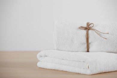 Photo of Rolled and folded soft towels on wooden table, space for text