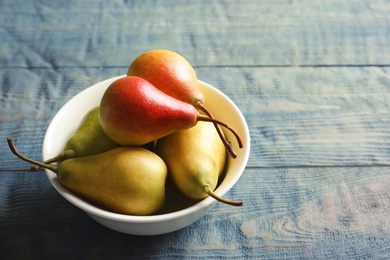 Photo of Bowl with ripe pears on wooden background. Space for text