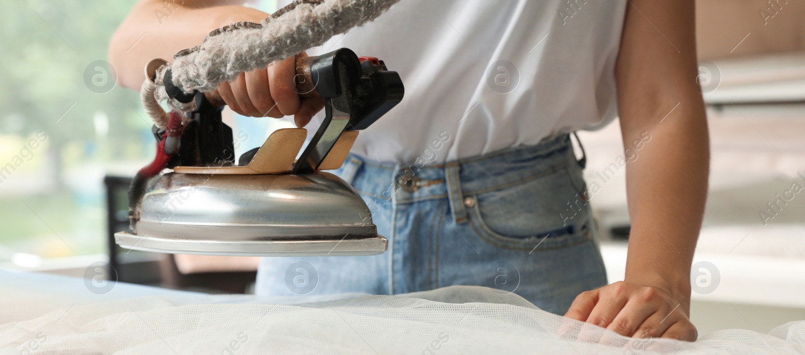 Image of Closeup view of female worker ironing laundry, banner design. Dry-cleaning service