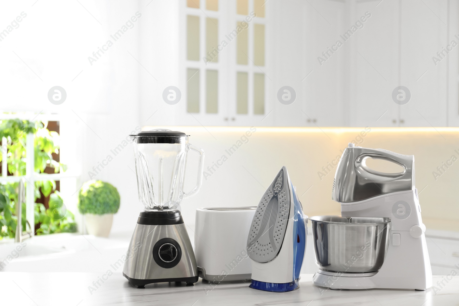 Photo of Set of modern home appliances on white marble table in kitchen