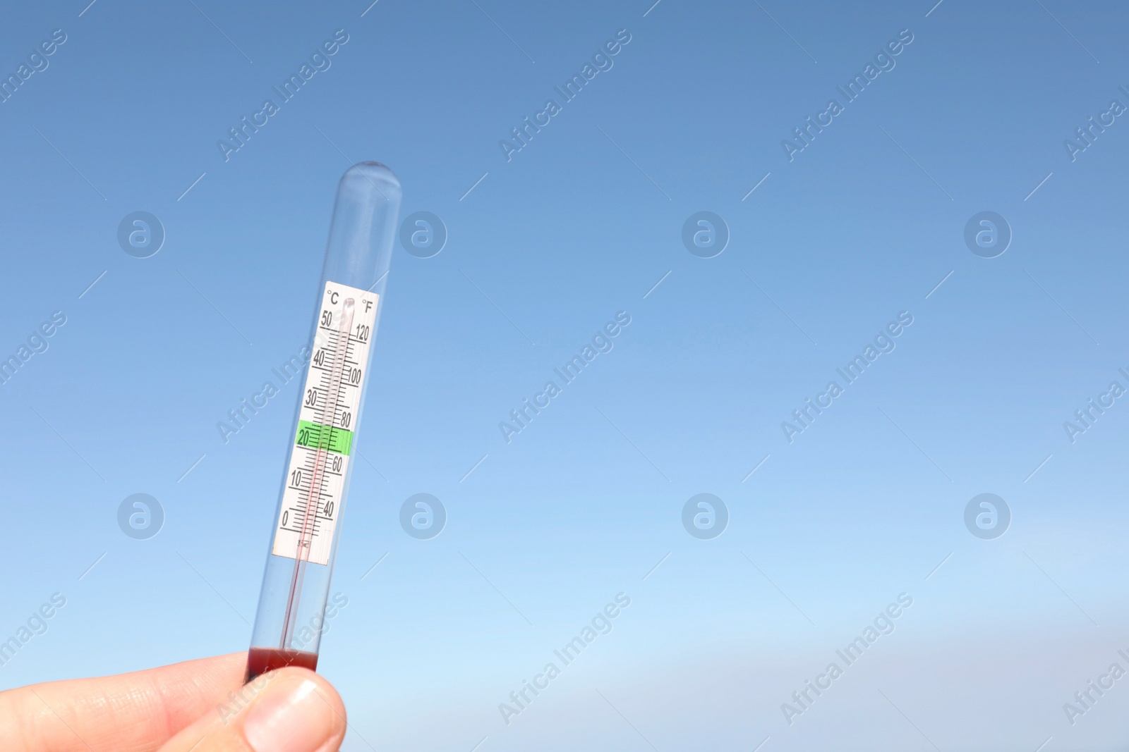 Photo of Woman holding weather thermometer against blue sky, space for text