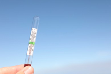 Photo of Woman holding weather thermometer against blue sky, space for text